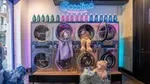 Lavatrice a gettoni Coccolino Wonder Wash. 8 lavatrici e flaconi di detersivo posizionati su di esse.