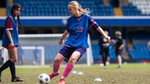 Giovane donna bionda che gioca a calcio con una divisa blu. Programma “Breaking Limits” di Rexona in azione al Chelsea.